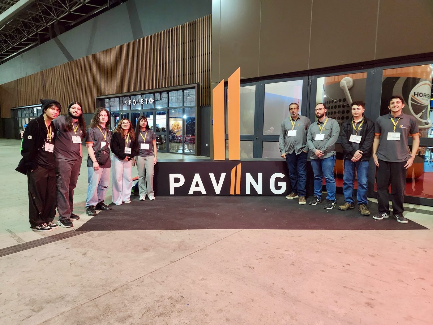 Equipe da T-Road Engenharia reunida em frente a estande de evento do setor de pavimentação